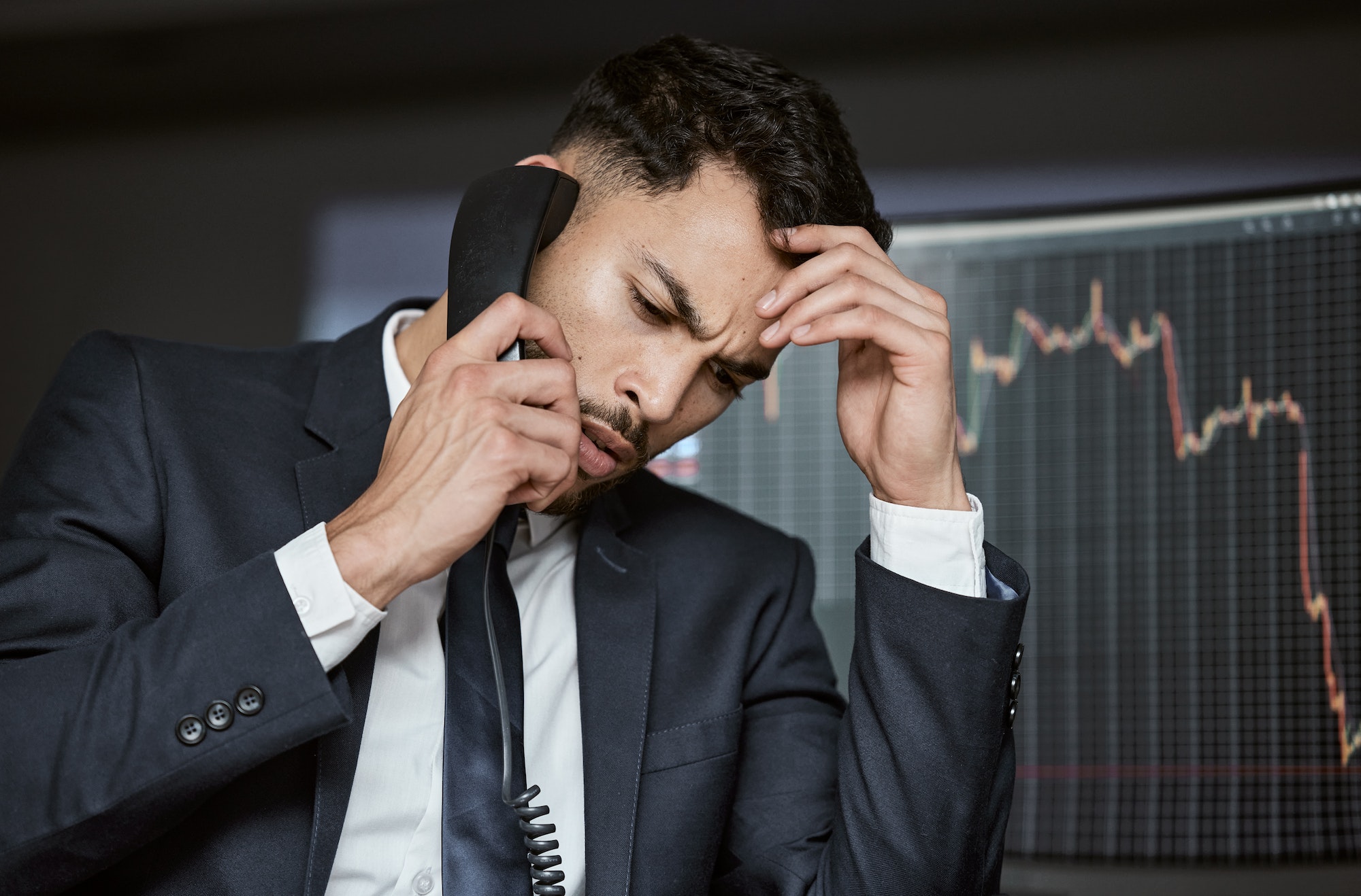 Stressed businessman on the phone, trading on the stock market during a financial crisis. Trader in