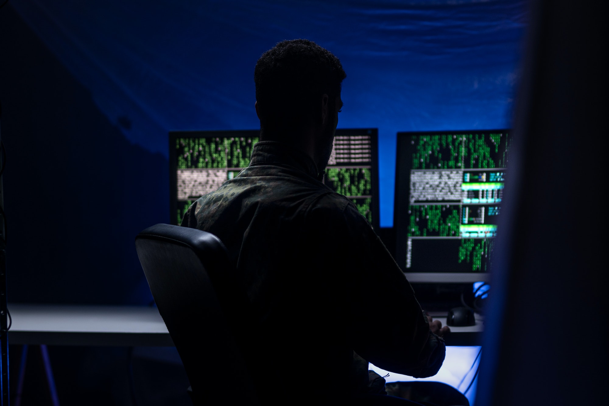 Anonymous hacker in military uniform on dark web, cyberwar concept.