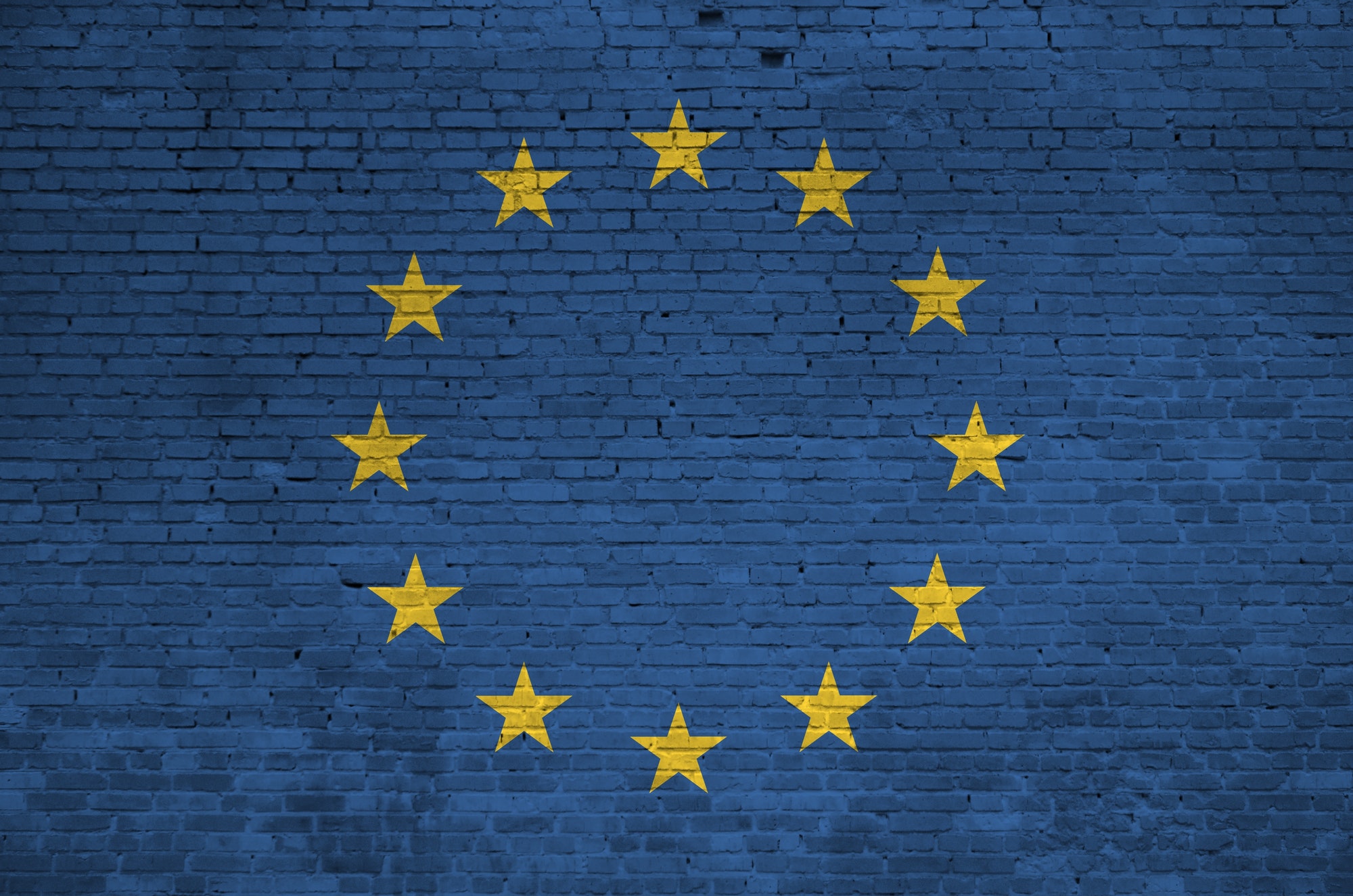European union flag depicted in paint colors on old brick wall close up