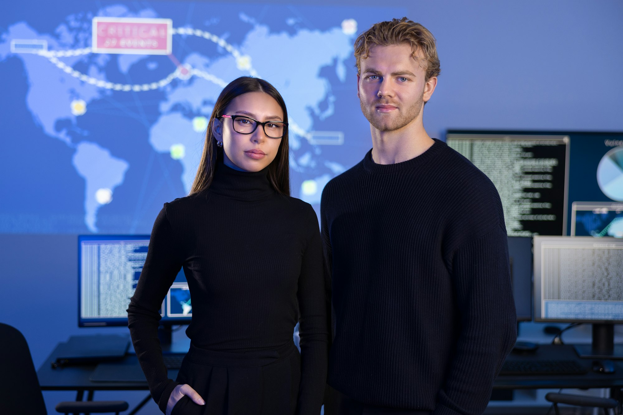 Professional and confident cyber security team in front of cybersecurity SIEM system with logs and