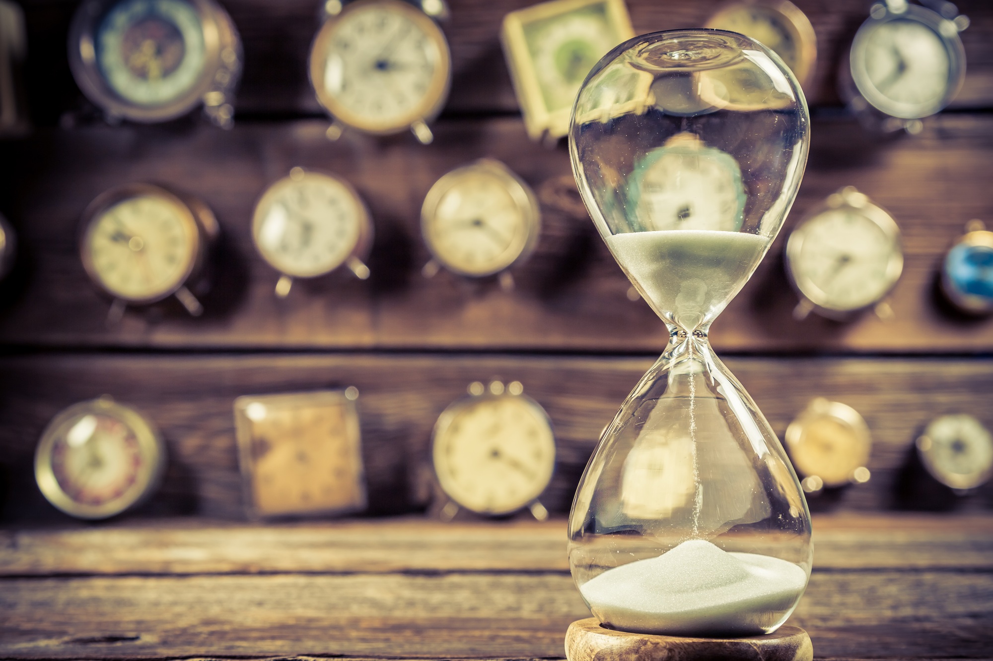 Aged hourglass on the background of clocks